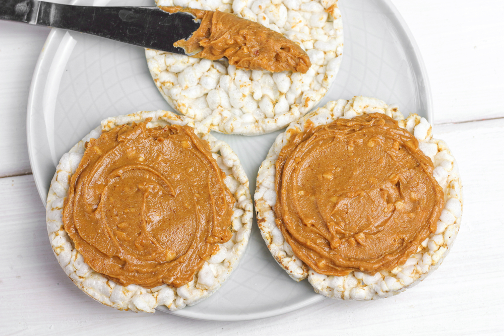 Travel snack: crunchy natural peanut butter sandwich with rice cake bread and knife with peanut butter on plate. Proper nutrition diet vegetarian breakfast 