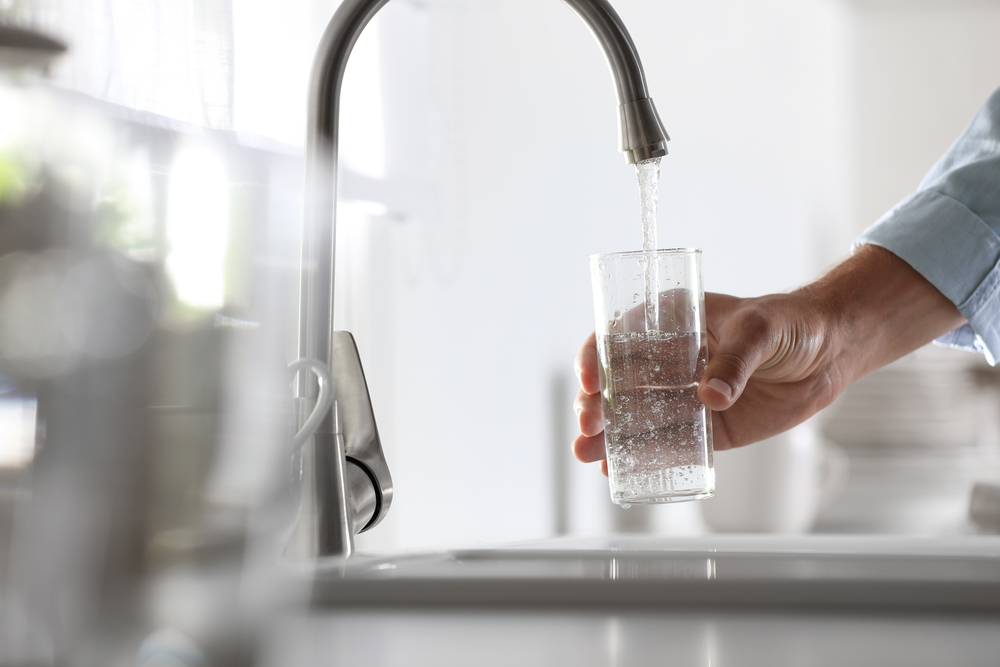 Hydration and Water Filters: Man pouring water into glass in kitchen, closeup 