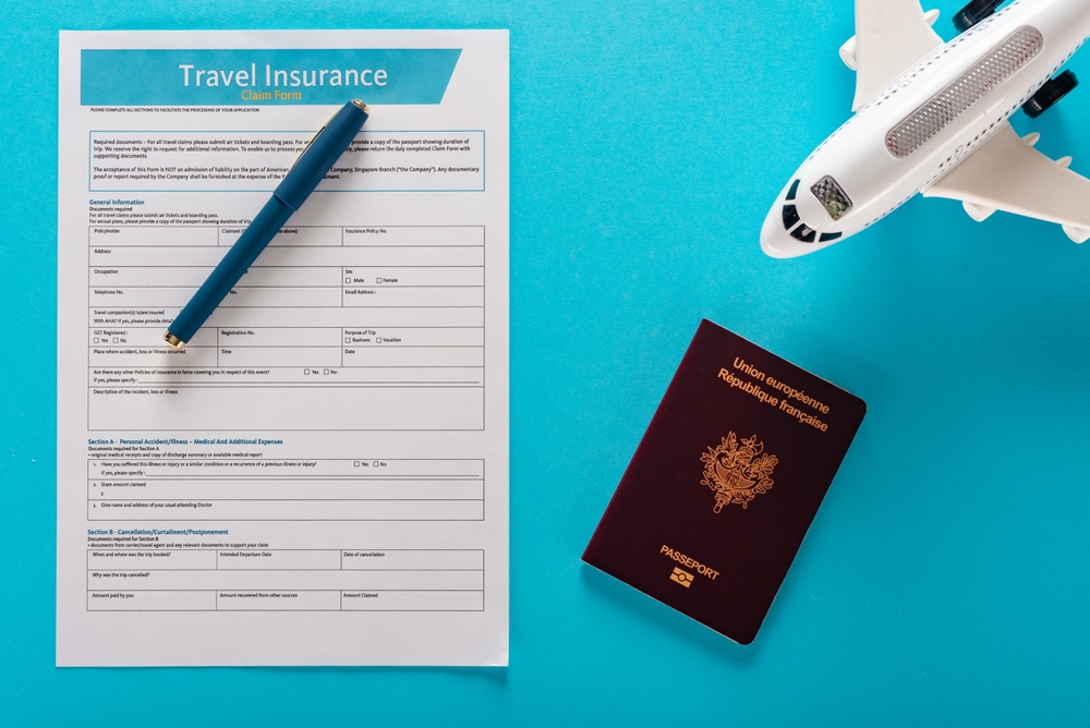 Travel Insurance: Travel insurance application form with airplane model and luggage on blue background, the forms do not contain personal data or licensed material 