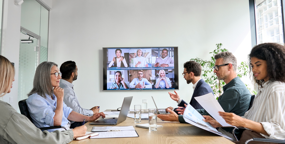 Cultural Etiquette: Diverse company employees having online business conference video call on tv screen monitor in board meeting room. 