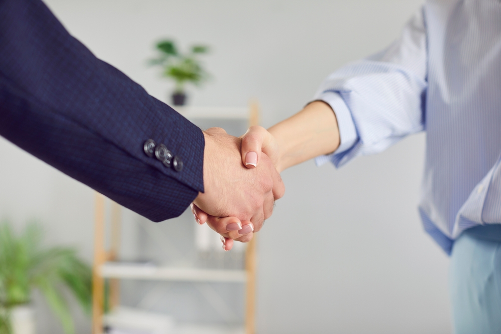 Cultural Etiquette: Strong handshake between professionals in a corporate environment as a symbol of trust and partnership. Close up of handshake between two professionals