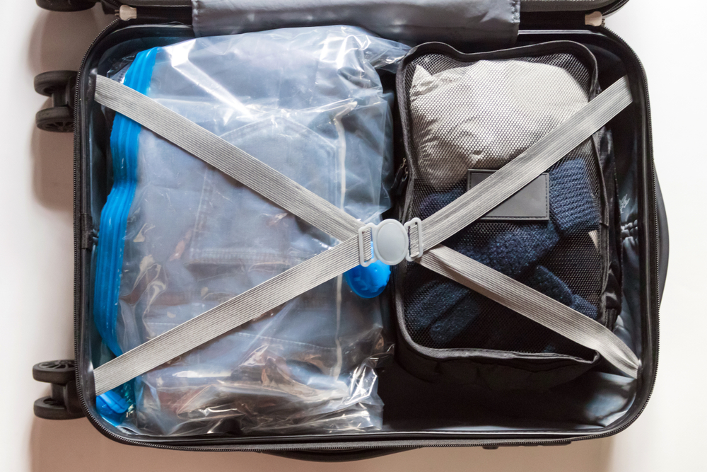 Genius Packing Hacks to Save Space and Time: Crossed belts on vacuum compress bag for clothes and expanded your space suitcase.