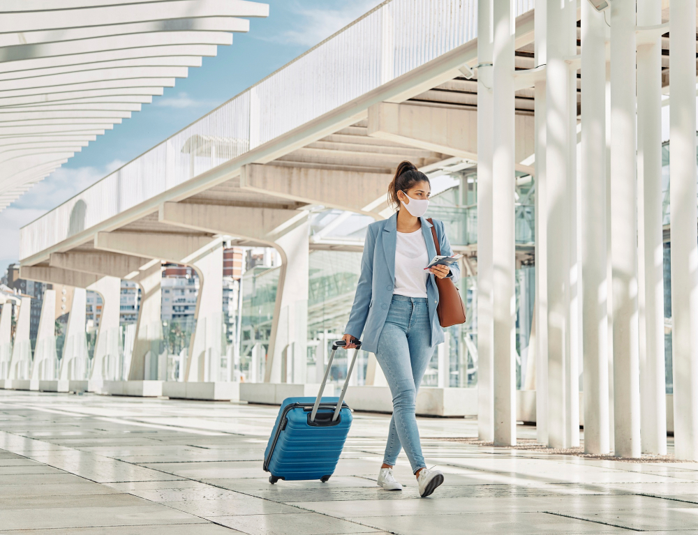 The Worst Places to Visit Without Travel Vaccinations: Woman with luggage during pandemic at the airport 