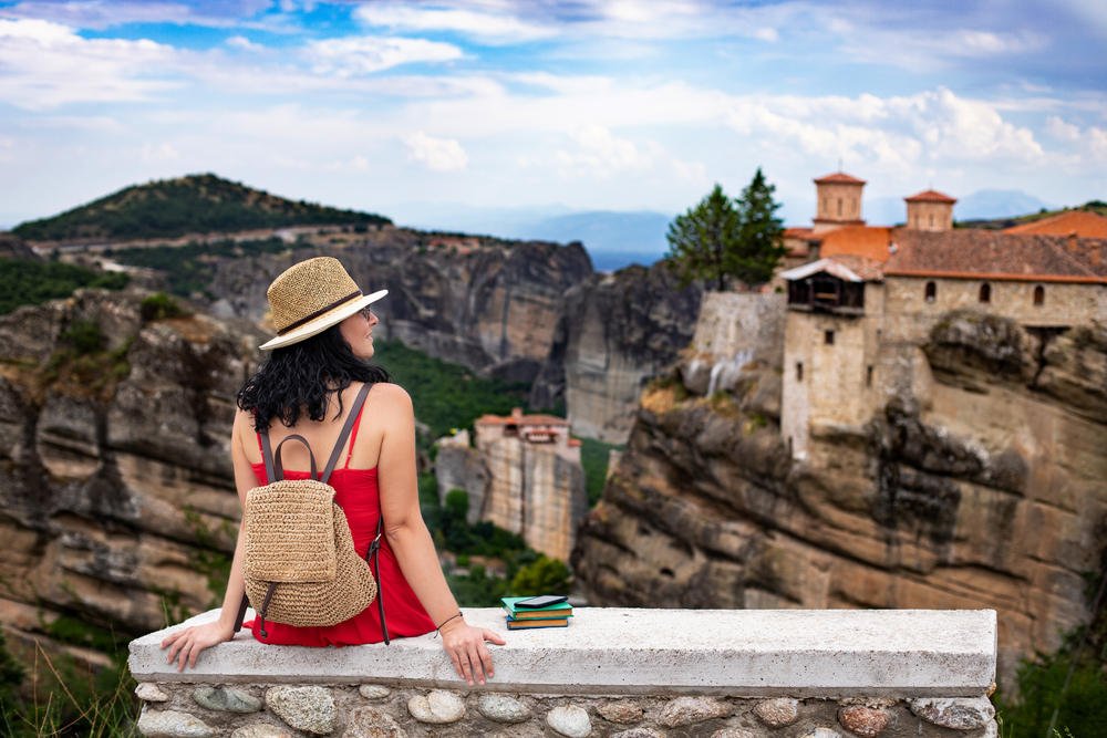 Walking Tours of Meteora: A red dressed woman traveling Meteora, Greece. Vacation concept in Greece.