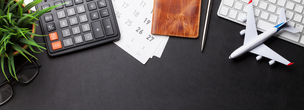 Tips for Finding Cheap Flights: A Step-by-Step Guide: Business trip concept. Accessories on desk table. Pc keyboard, passport, calendar and airplane toy. Top view with copy space 