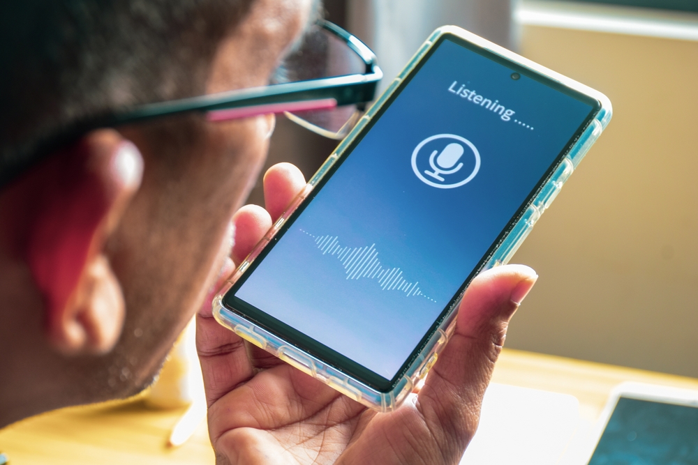 How to Overcome Language Barriers While Traveling: Close-up of a South Asian man talking to a voice translator mobile application. Selective focus.