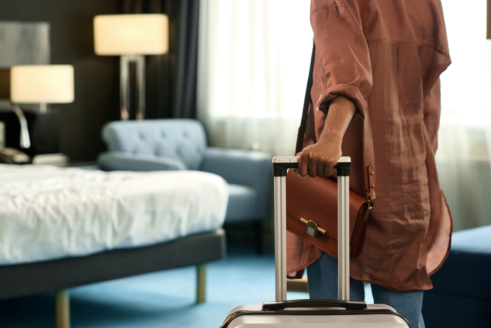 What Not To Do When Booking Hotels in Zadar: Close up of unrecognizable Black woman entering hotel room and holding suitcase upon travelling to resort copy space 