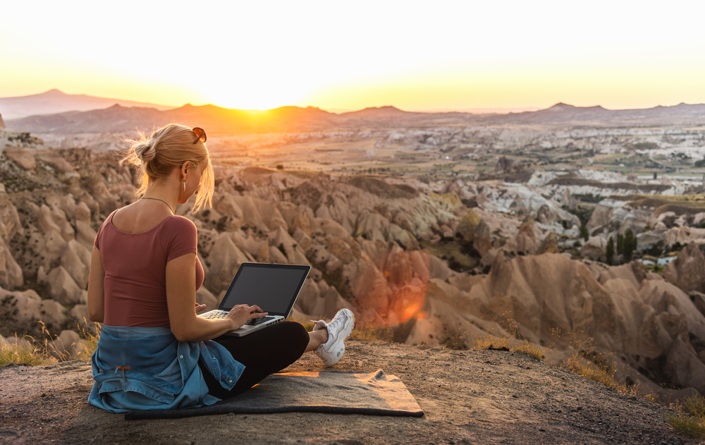 The Biggest Safety Mistakes People Make When Traveling Solo: photo of a young lady on vacation working on a laptop 