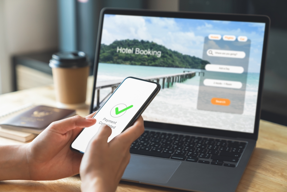 What Not To Do When Booking Hotels in Zadar: Hand using laptop and booking hotel on website for vacation after a long work and payment completed message on mobile, Summer holiday concept.