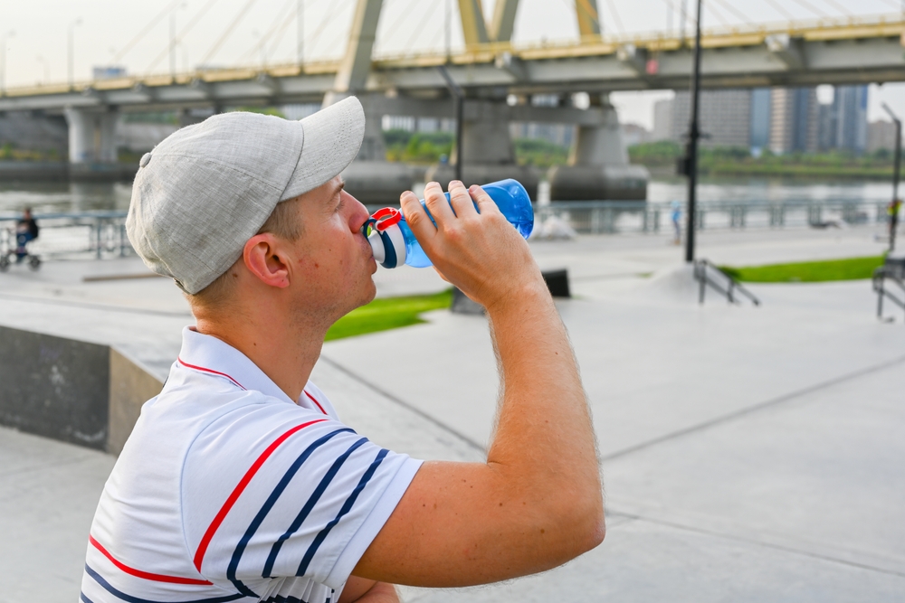 What Not to Do When Drinking Water Abroad: Young man in white T-shirt and gray cap drinking water in skateboard center 